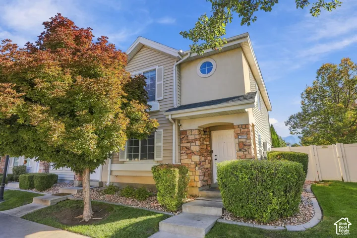 Two-story exterior featuring a stone veneer entryway, horizontal siding, decorative shutters, and a circular accent window