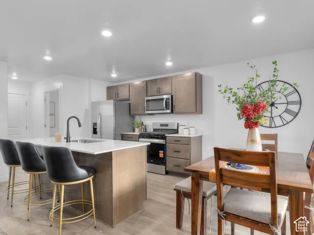 Kitchen featuring wood-finish cabinetry, a central island with a stone-composite countertop, stainless steel appliances, a matte black faucet, and recessed lighting