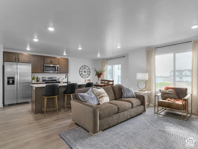 Kitchen featuring dark wood cabinetry, stainless steel appliances, kitchen island with seating, and wood-finish flooring