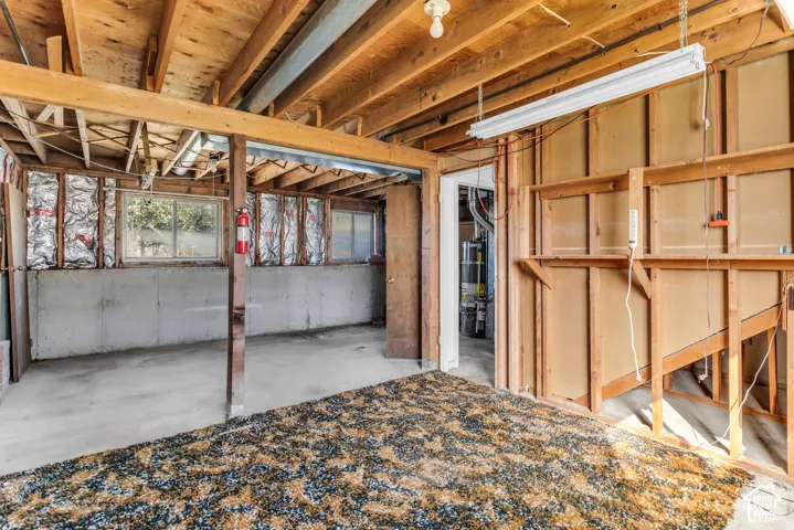 Unfinished lower level featuring exposed wood joist ceilings, concrete foundation walls, dual-pane windows, and a water heater