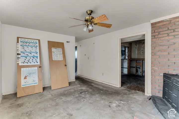 Exposed brick fireplace with an integrated metal wood-burning stove and a ceiling-mounted light fixture with a multi-blade fan