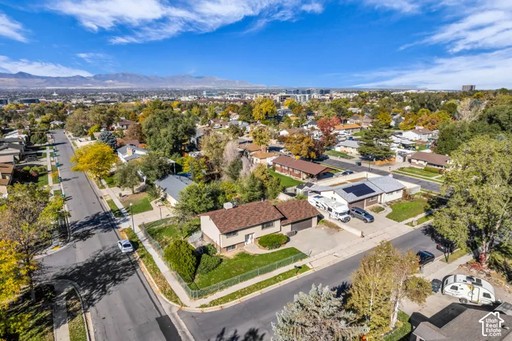 Corner lot property featuring an asphalt-shingle roof, attached garage, fenced front lawn, and distant mountain backdrop