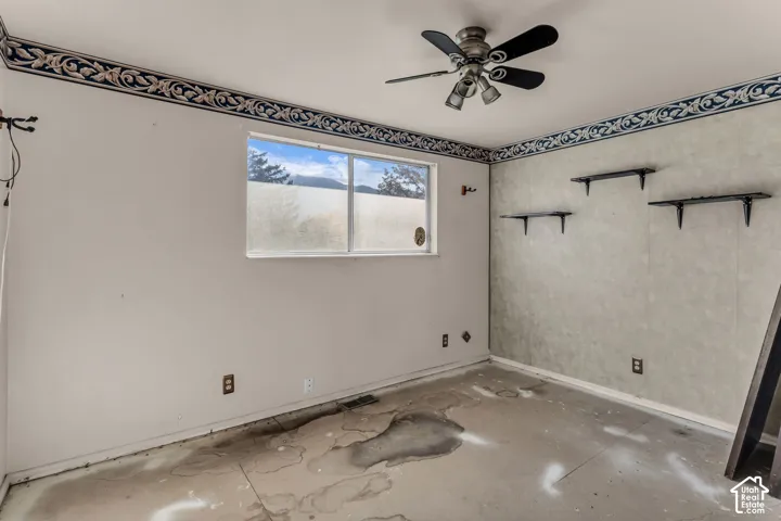 Interior room featuring a sliding window, ceiling-mounted light fixture with fan blades, and three wall-mounted floating shelves