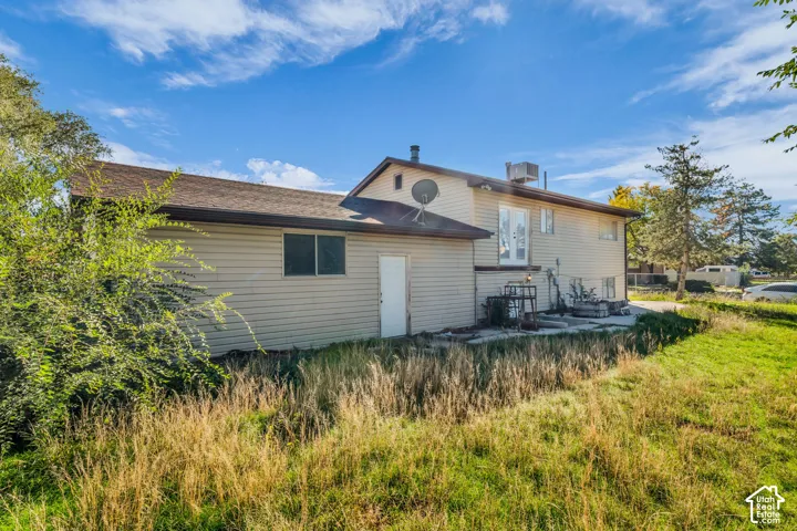 Exterior featuring horizontal siding, a gabled roofline, concrete patio, and mature landscaping