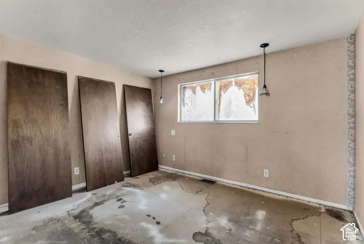 Room featuring textured wall finishes, three solid wood doors, and dual pendant lighting fixtures