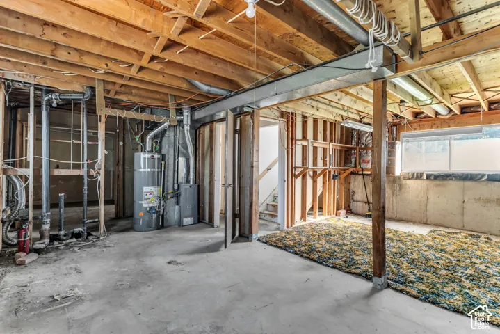 Unfinished lower level featuring exposed wood framing, concrete foundation walls, exposed ceiling joists, a water heater, and an integrated steel support beam