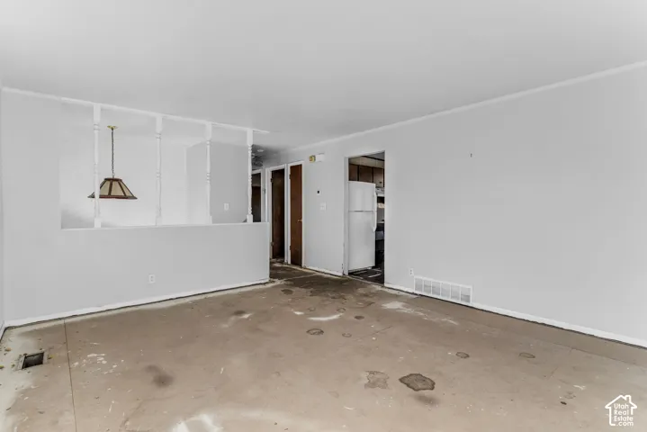 Open interior space featuring a partial room divider with spindle detailing, hanging pendant lighting, and multiple interior wood-finish doors