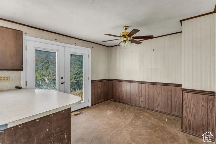 Dual glass-paneled exterior doors, wood-finish wainscoting, ceiling-mounted fan with integrated lighting, and solid-surface countertop with built-in cabinetry