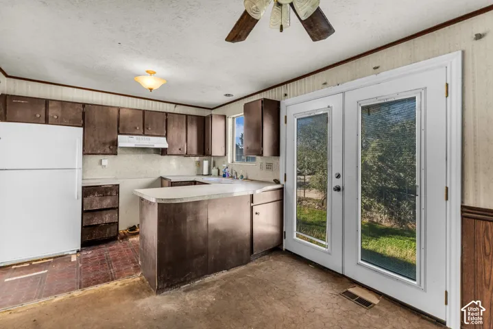 Kitchen featuring stained-wood cabinetry, a peninsula counter, a built-in range hood, and double-glass paneled doors