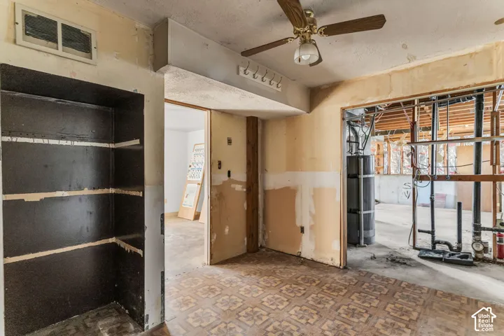 Interior space featuring patterned vinyl flooring, a built-in recessed storage alcove, and an overhead ceiling fan