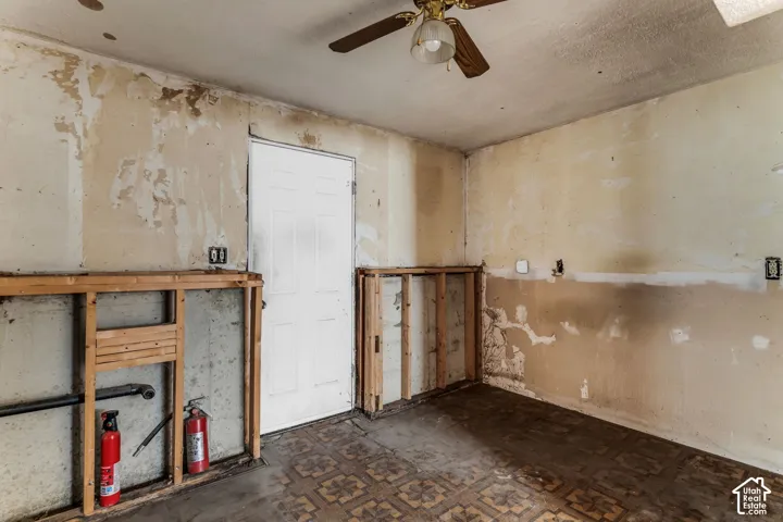 Interior room featuring exposed wood framing, a white paneled door, and a ceiling-mounted light fixture with fan blades