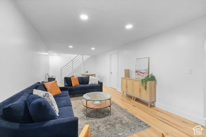 Open-concept room featuring wood-finish flooring, recessed lighting, and a white staircase with horizontal metal railing