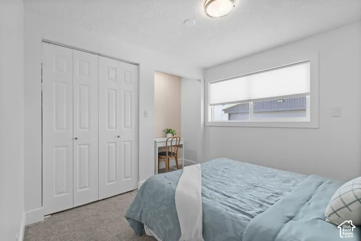 Bedroom featuring neutral carpeting, white interior doors with paneled detailing, a dedicated recessed alcove, and a horizontal window with a cellular shade
