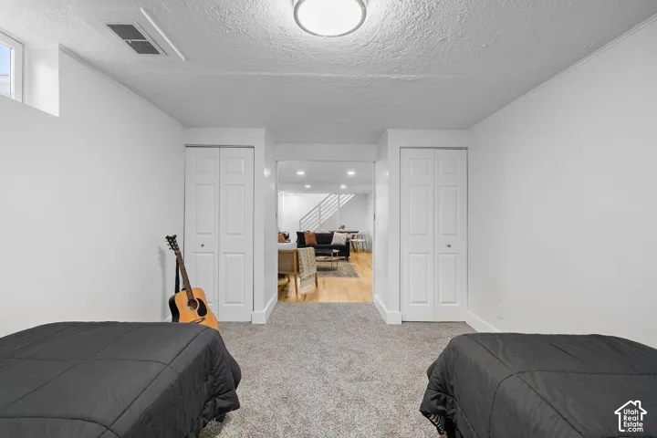 Room featuring neutral carpeting, dual white bi-fold closets, and a flush-mount ceiling light fixture