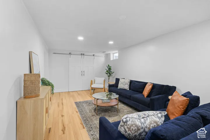 Neutral interior space featuring wood-finish flooring, recessed lighting, and white sliding barn doors with polished metal hardware