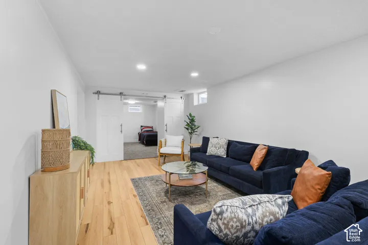 Interior space featuring light-toned wood-finish flooring, recessed lighting, and white sliding barn doors with stainless steel hardware