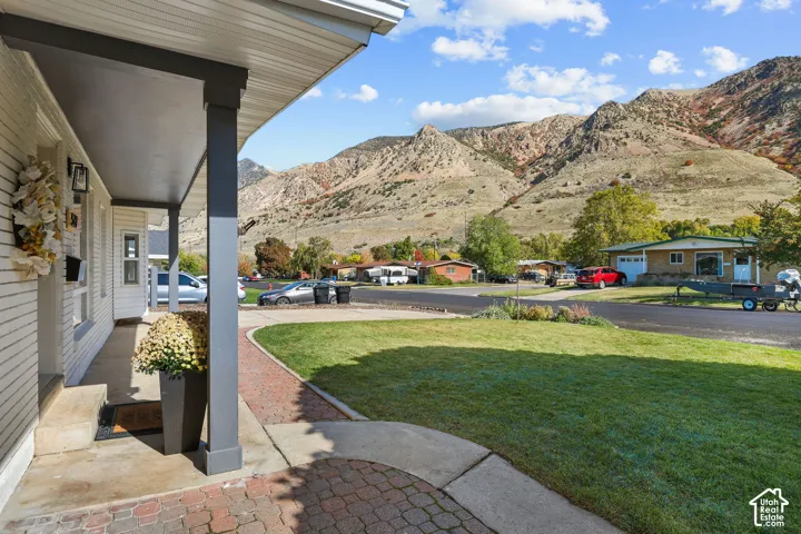 Covered front porch featuring a brick-paved walkway, siding exterior, and mountain backdrop