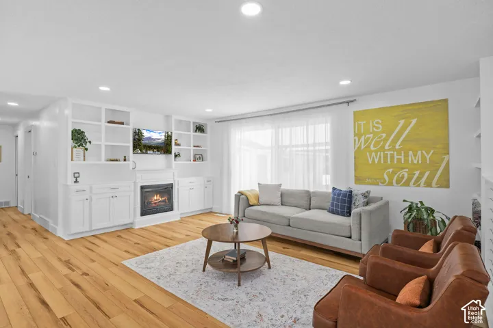 Living area featuring wood-finish flooring, recessed lighting, and built-in floor-to-ceiling cabinetry surrounding a fireplace
