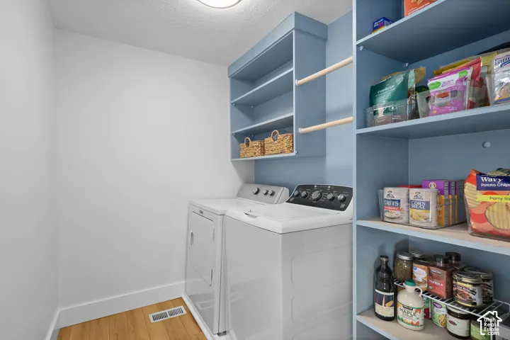 Laundry area featuring wood-finish flooring, blue custom built-in cabinetry, and integrated open shelving