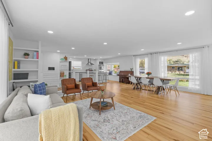 Open-concept interior featuring light wood-finish flooring, recessed lighting, built-in shelving, and large windows
