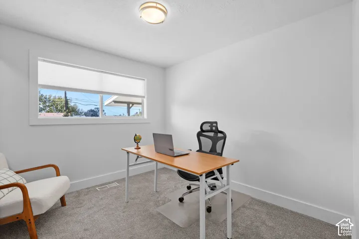 Room featuring neutral wall tones, gray carpeting, a single-pane horizontal window, and a circular flush-mount ceiling light fixture