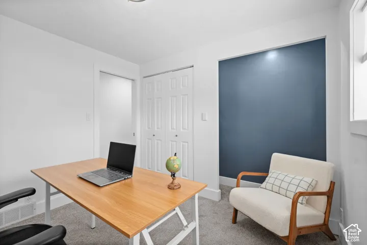 Interior room featuring neutral wall-to-wall carpeting, dual-pane window, bi-fold closet doors, and a contrasting blue accent wall