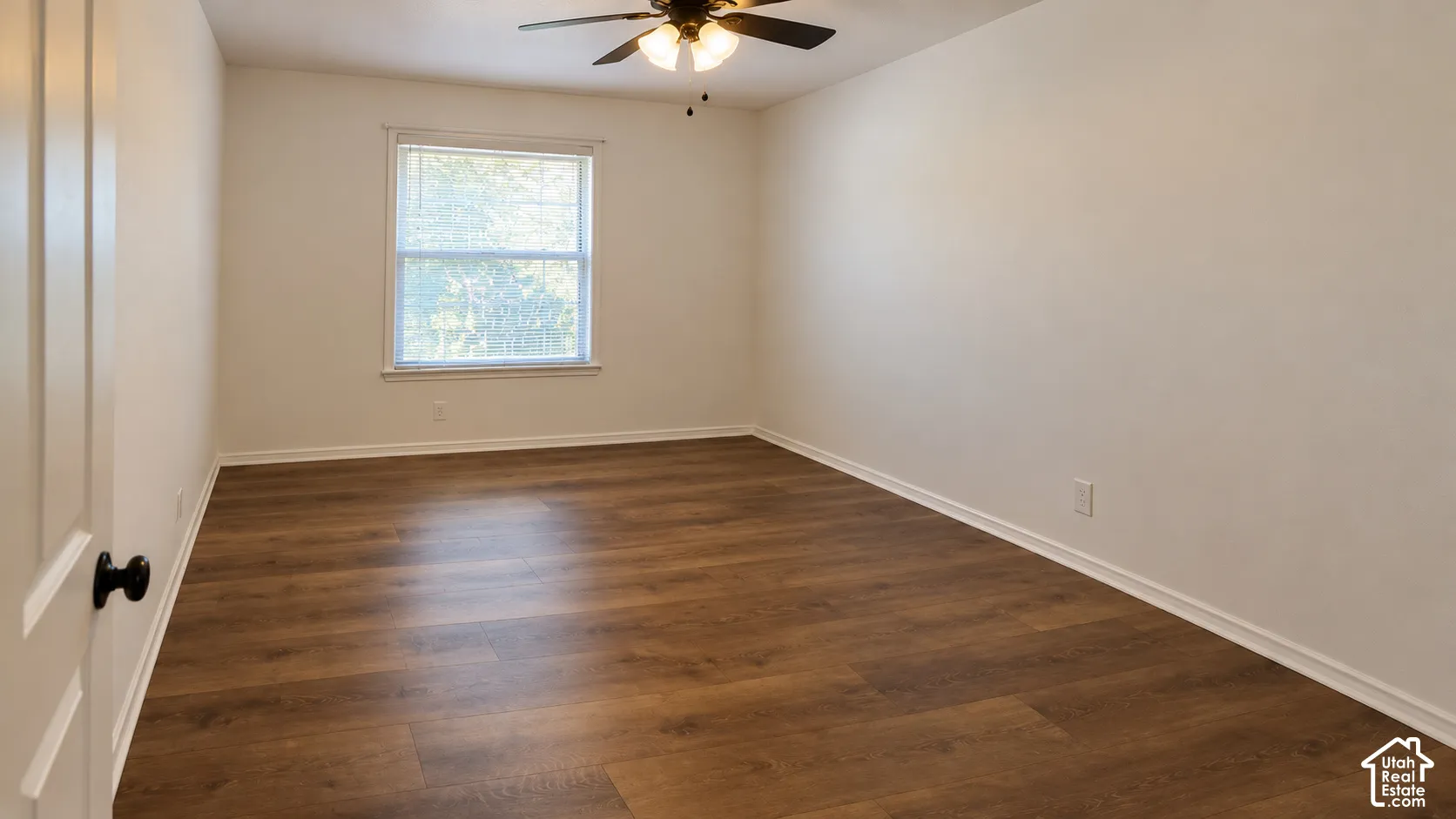 Neutral interior featuring wood-finish flooring, a multi-pane window, and an integrated ceiling fan with light fixture