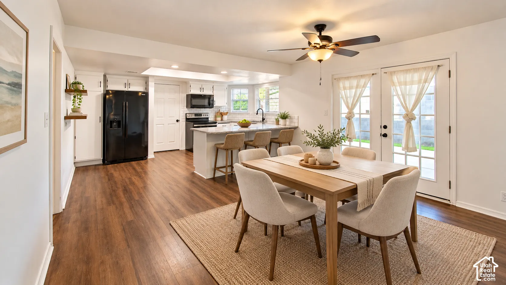 Kitchen featuring wood-finish flooring, white cabinetry, a stone-surface breakfast bar, a ceiling fan, and double glass-paned exterior doors
