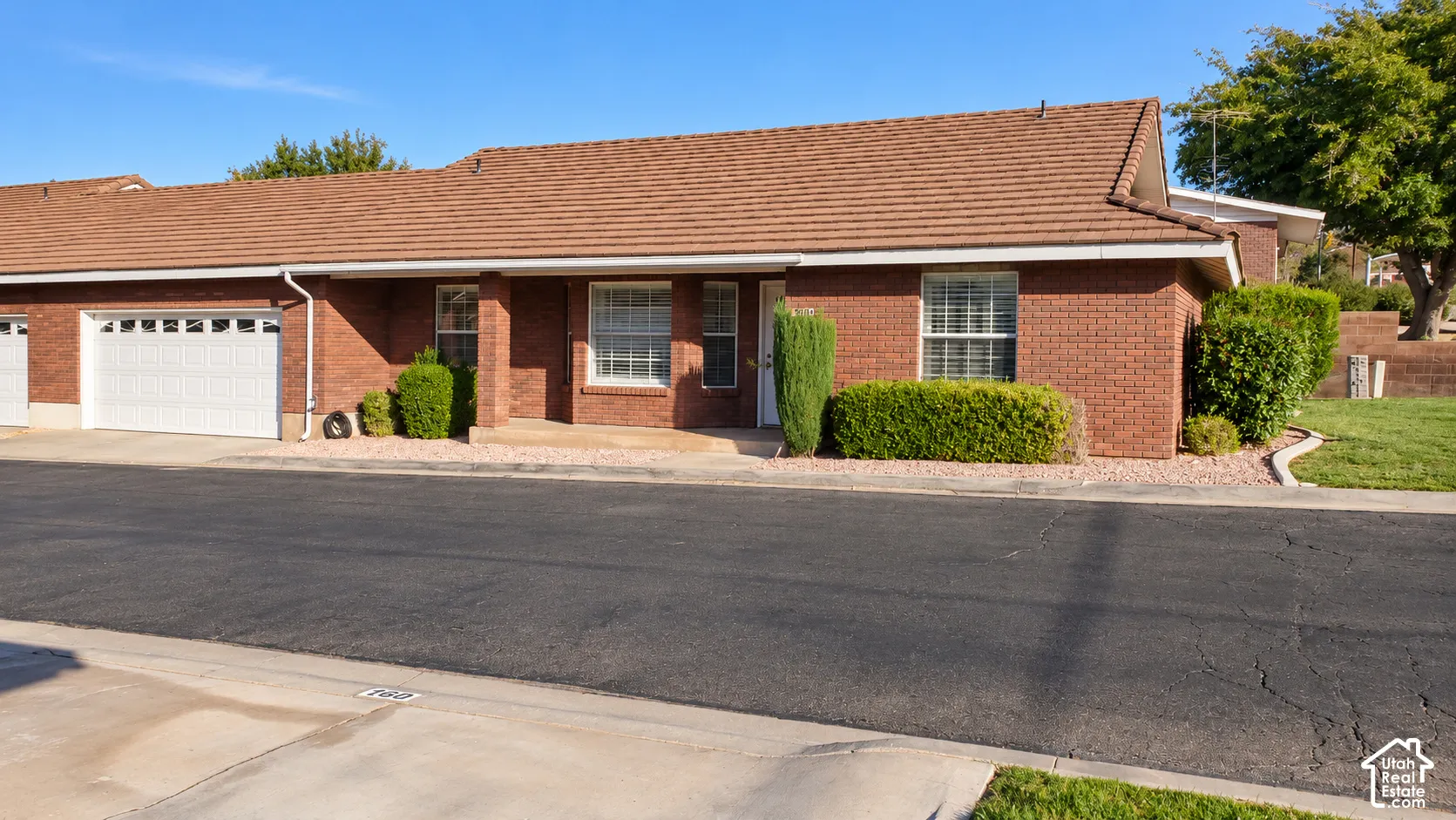 Single-story red brick exterior featuring a tiled roof, multi-pane windows, and a built-in garage
