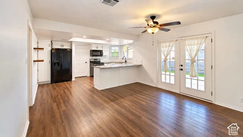 Kitchen featuring stone countertops, white cabinetry, integrated black appliances, wood-finish flooring, and dual French doors