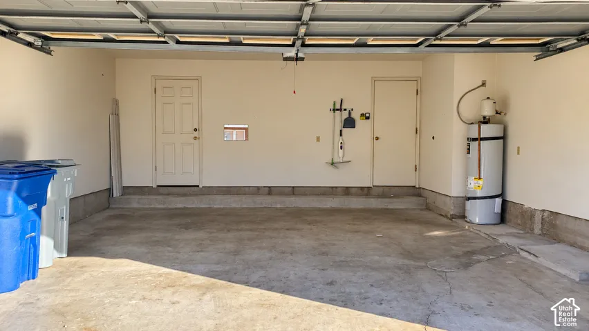 Two-car garage featuring a concrete floor, dual entry doors, and a dedicated water heater