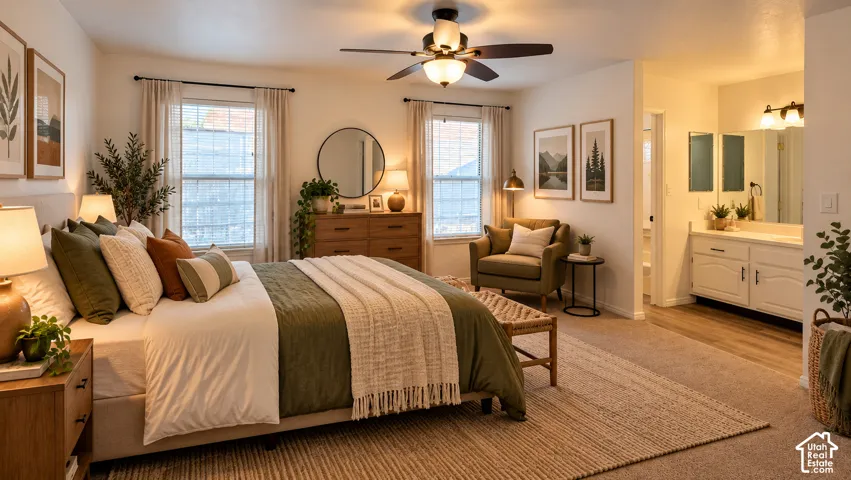 Neutral-toned bedroom featuring wall-to-wall carpeting, dual windows with natural light, a multi-blade ceiling fan with integrated lighting, and a white vanity with an expansive wall mirror
