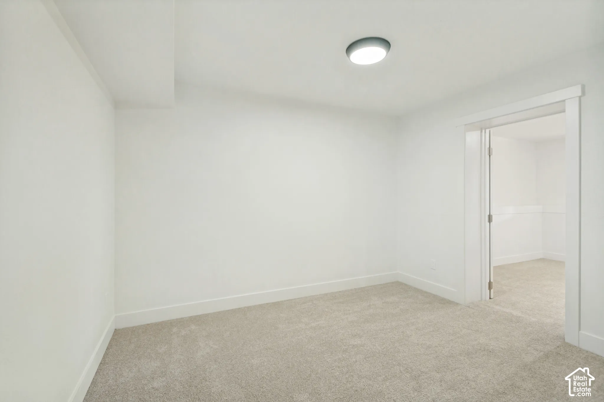 Neutral-toned wall-to-wall carpeting, crisp white walls, and a recessed ceiling light fixture