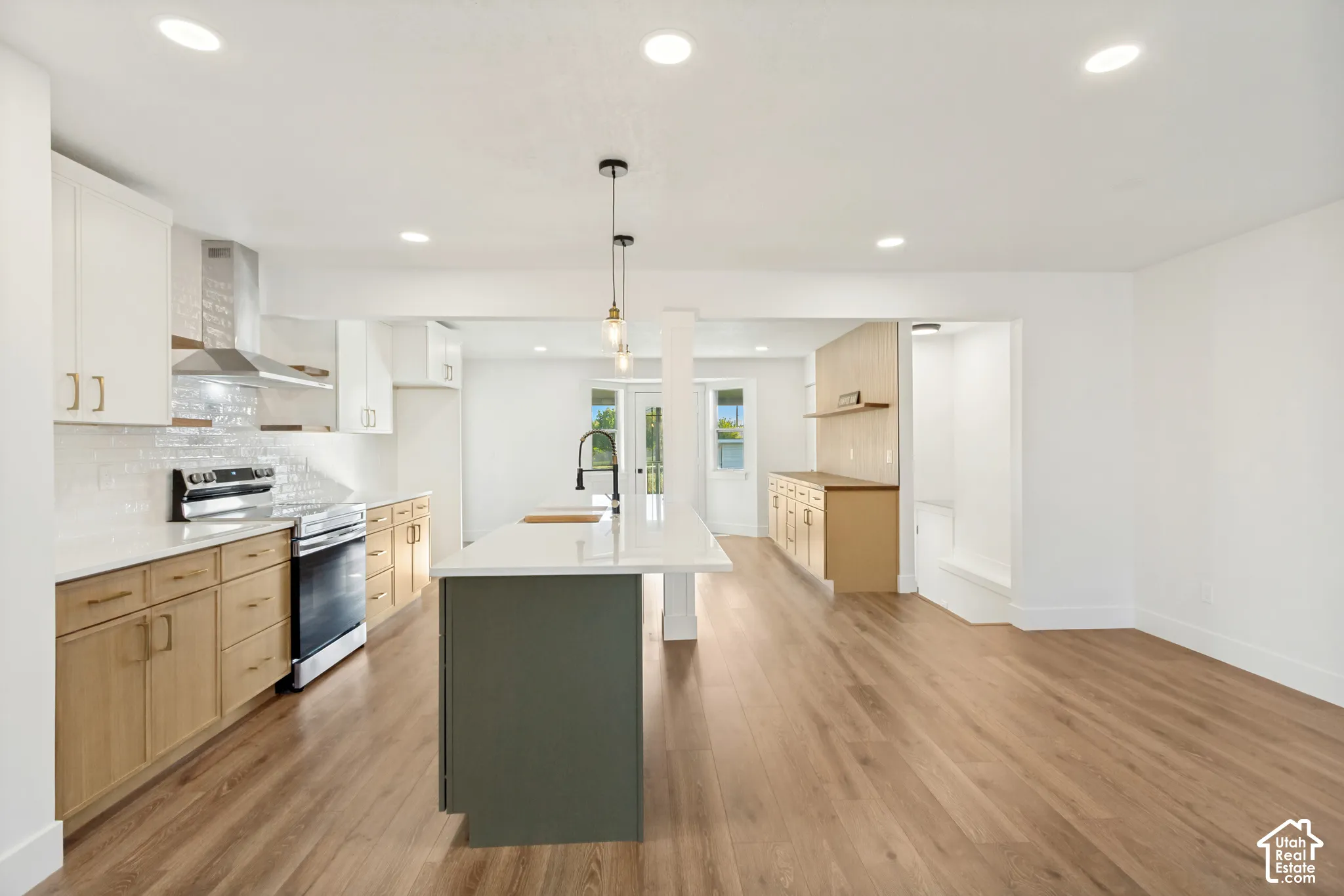 Kitchen featuring wood-finish cabinetry, white countertops, a center island with a matte black faucet, subway tile backsplash, and recessed lighting