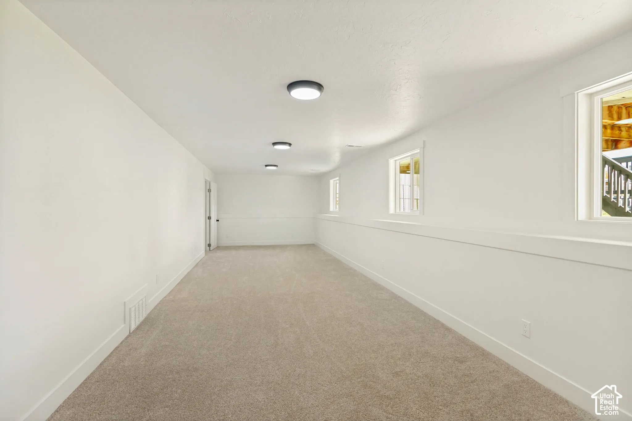 Neutral-toned carpeting, crisp white wall finish, recessed ceiling lighting, and multiple windows with white trim