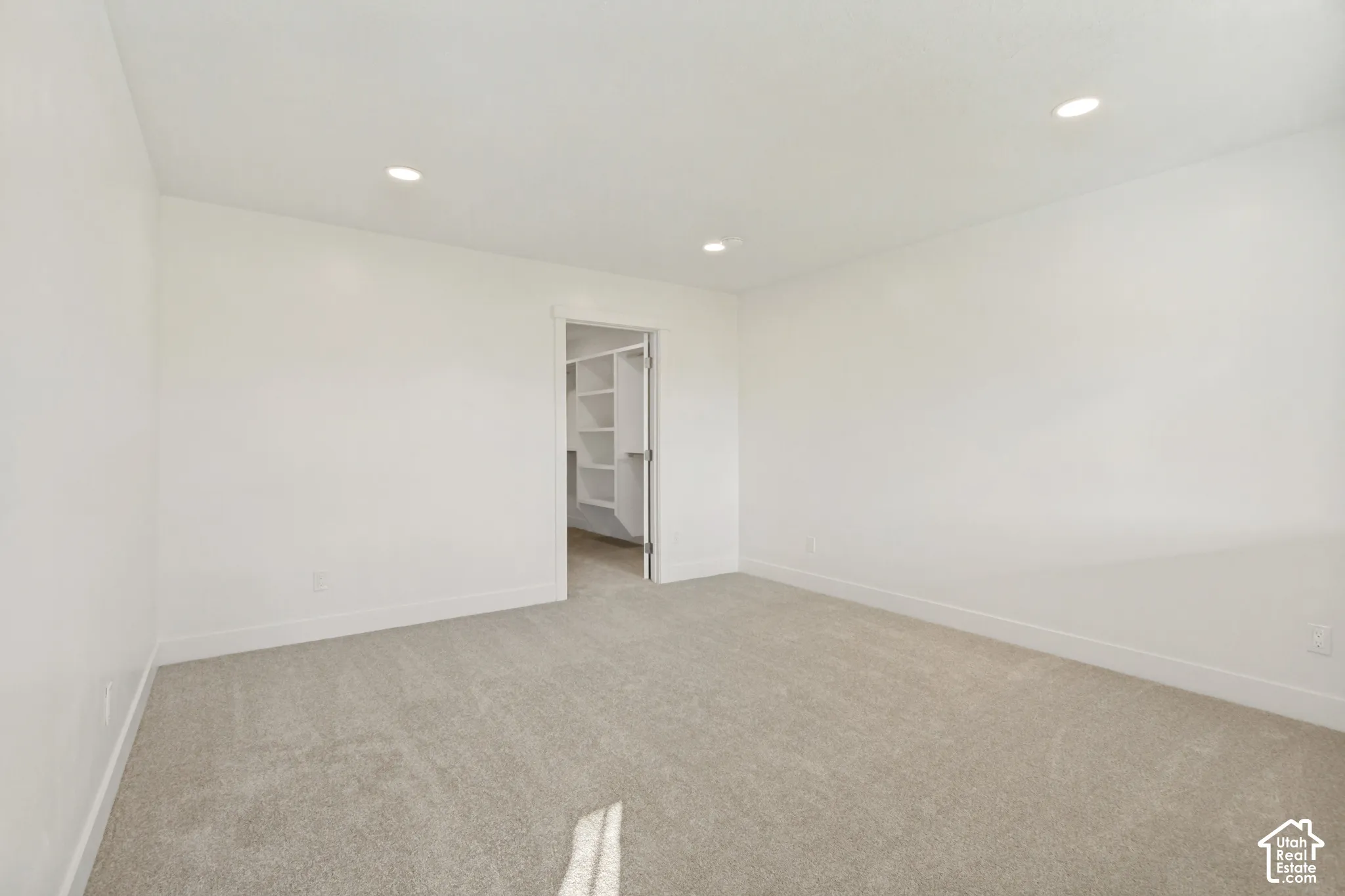 Neutral-toned carpeting, recessed ceiling lighting, and walk-in storage featuring built-in shelving