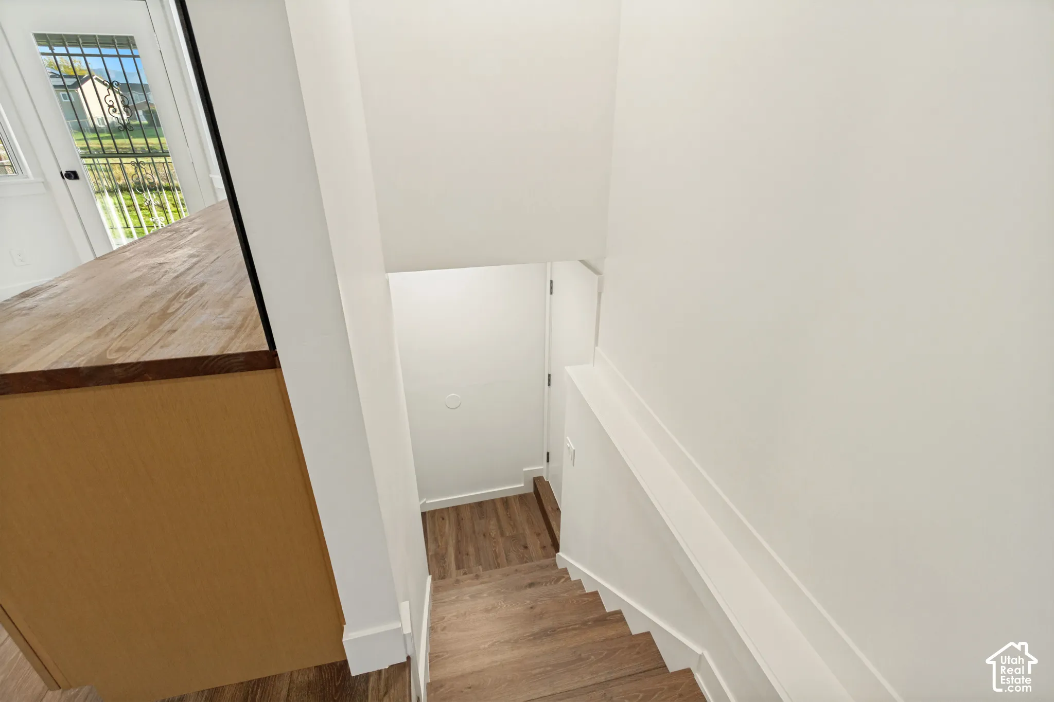 Staircase featuring wood-finish flooring and a built-in kitchen peninsula with a wood-grain countertop
