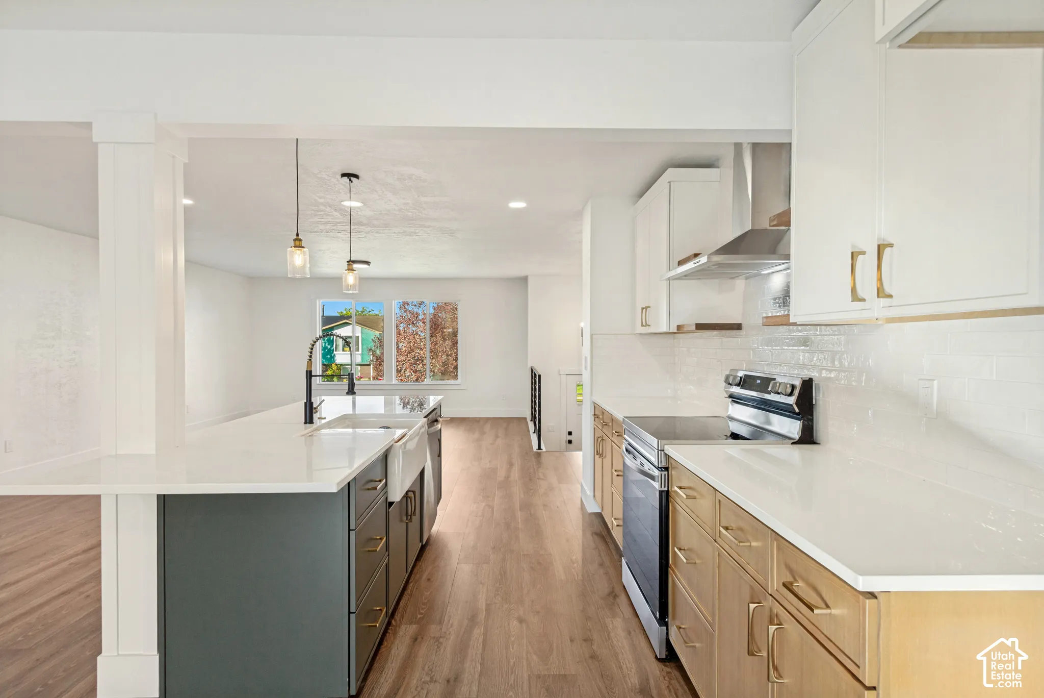 Kitchen featuring a spacious island with a farmhouse-style sink, quartz countertops, two-tone cabinetry, stainless steel appliances, and wood-finish flooring