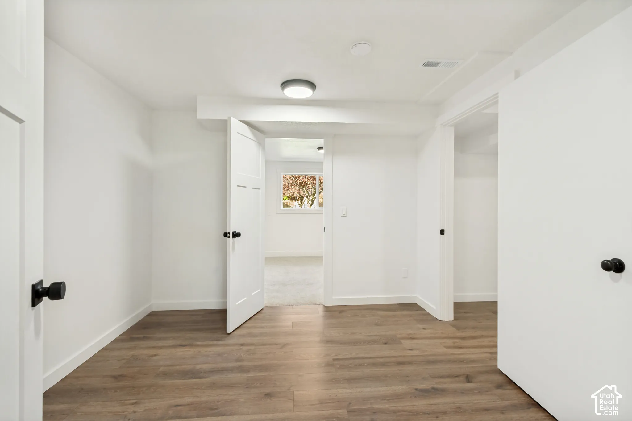 Interior space featuring wood-finish flooring, white walls, shaker-style interior doors, and matte black hardware