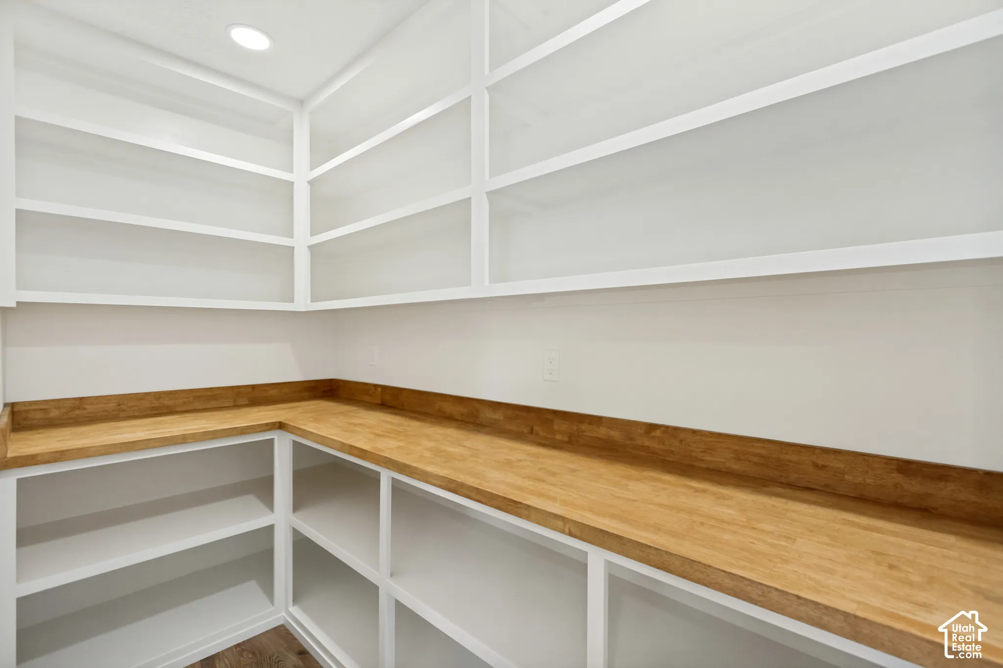 Built-in pantry featuring white shelving, wood-finish countertops with integrated backsplash, and recessed ceiling lighting