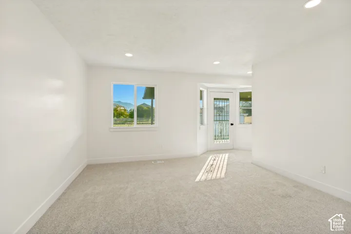 Neutral interior space featuring carpeted flooring, recessed lighting, and a single-light exterior door with glass panels