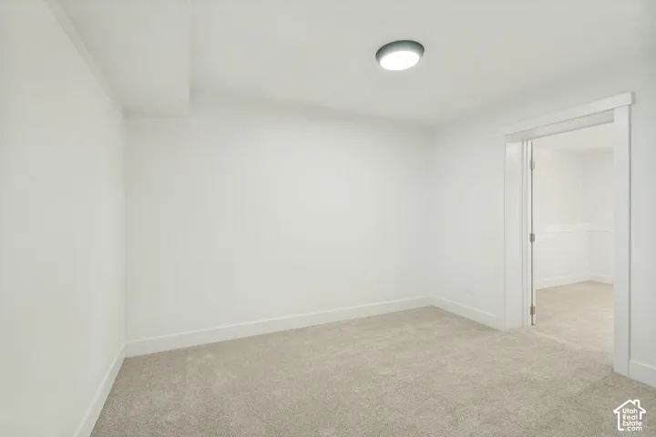 Neutral-toned wall-to-wall carpeting, crisp white walls, and a recessed ceiling light fixture