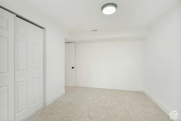 Neutral-toned carpeting, white interior walls, sliding panel closet doors, and flush-mount circular ceiling lighting
