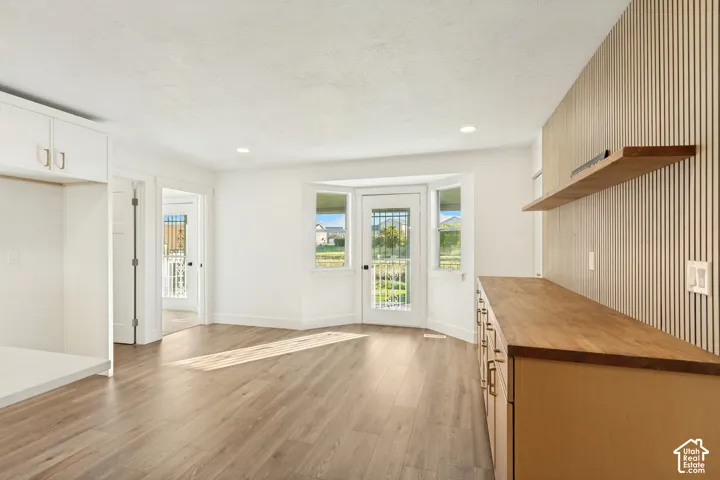 Room featuring wood-finish flooring, a wood-slat accent wall, built-in cabinetry with a wood countertop, and a bay window configuration with a glass-paneled door