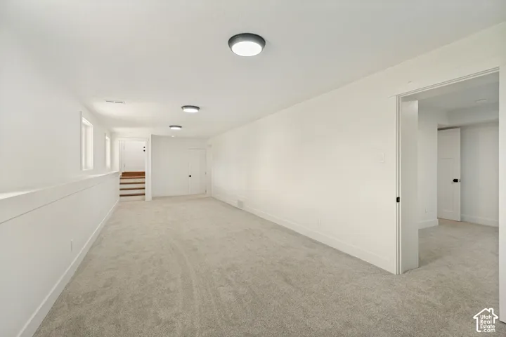 Neutral-toned wall-to-wall carpeting, recessed ceiling lighting, and crisp white wall finishes