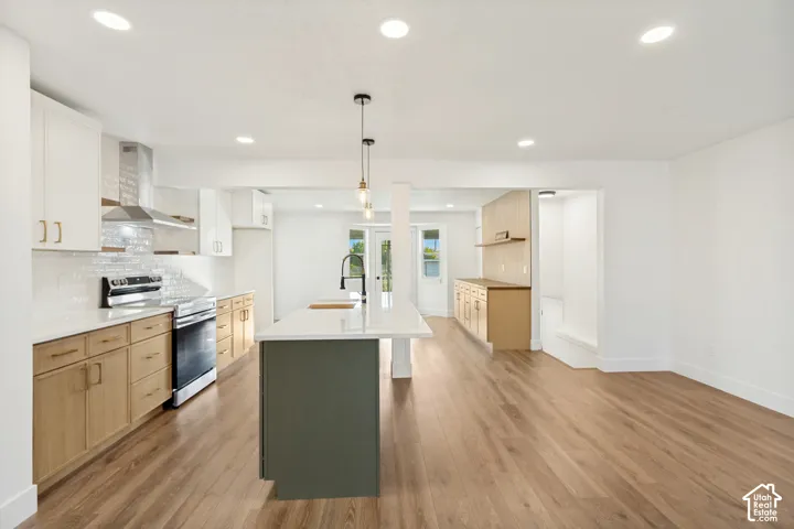 Kitchen featuring wood-finish cabinetry, white countertops, a center island with a matte black faucet, subway tile backsplash, and recessed lighting