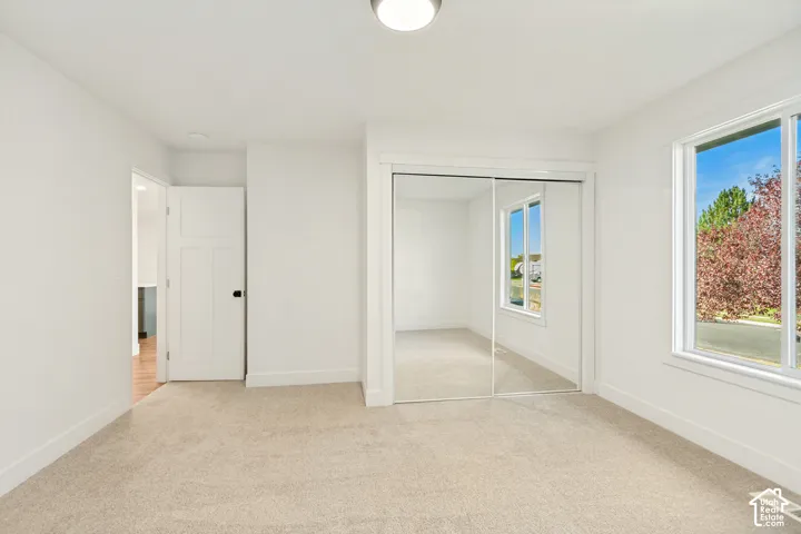 Neutral-toned wall-to-wall carpeting, sliding mirrored closet doors, and a single-pane window