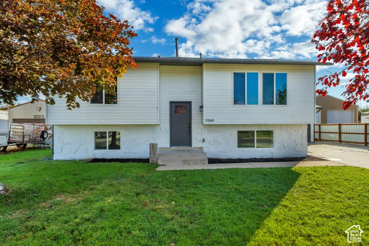 Split-level exterior featuring white horizontal siding, stone-textured lower facade, front door with glass insert, and concrete entry steps