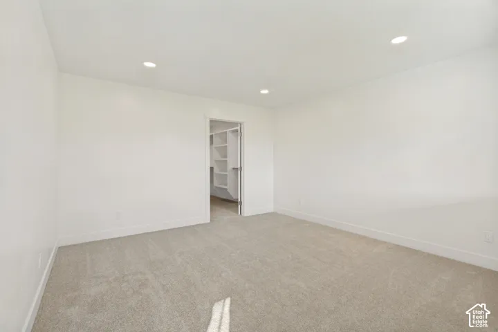 Neutral-toned carpeting, recessed ceiling lighting, and walk-in storage featuring built-in shelving