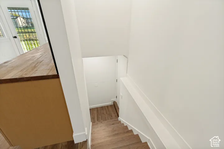 Staircase featuring wood-finish flooring and a built-in kitchen peninsula with a wood-grain countertop